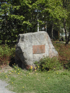 Suurikokoinen kivi, jossa on muistolaatta.