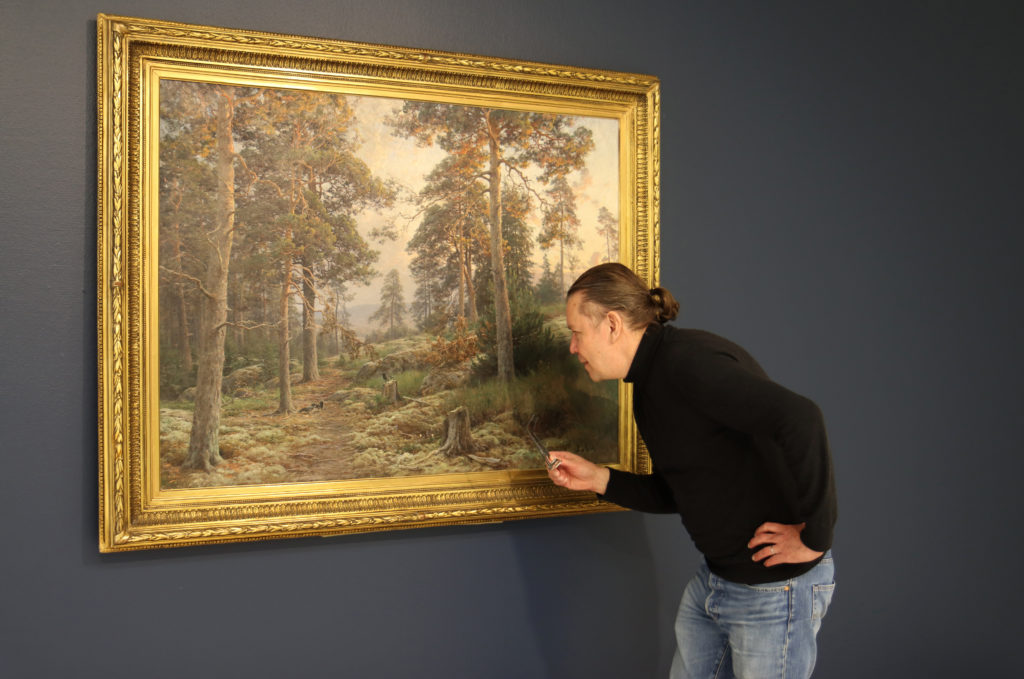 Teppo Jokinen tutkii Berndt Lindholmin maalausta Ilta metsässä 1892–93
