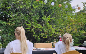 Kuvassa kaksi lasta istumassa selin ja tekemässä taidetta